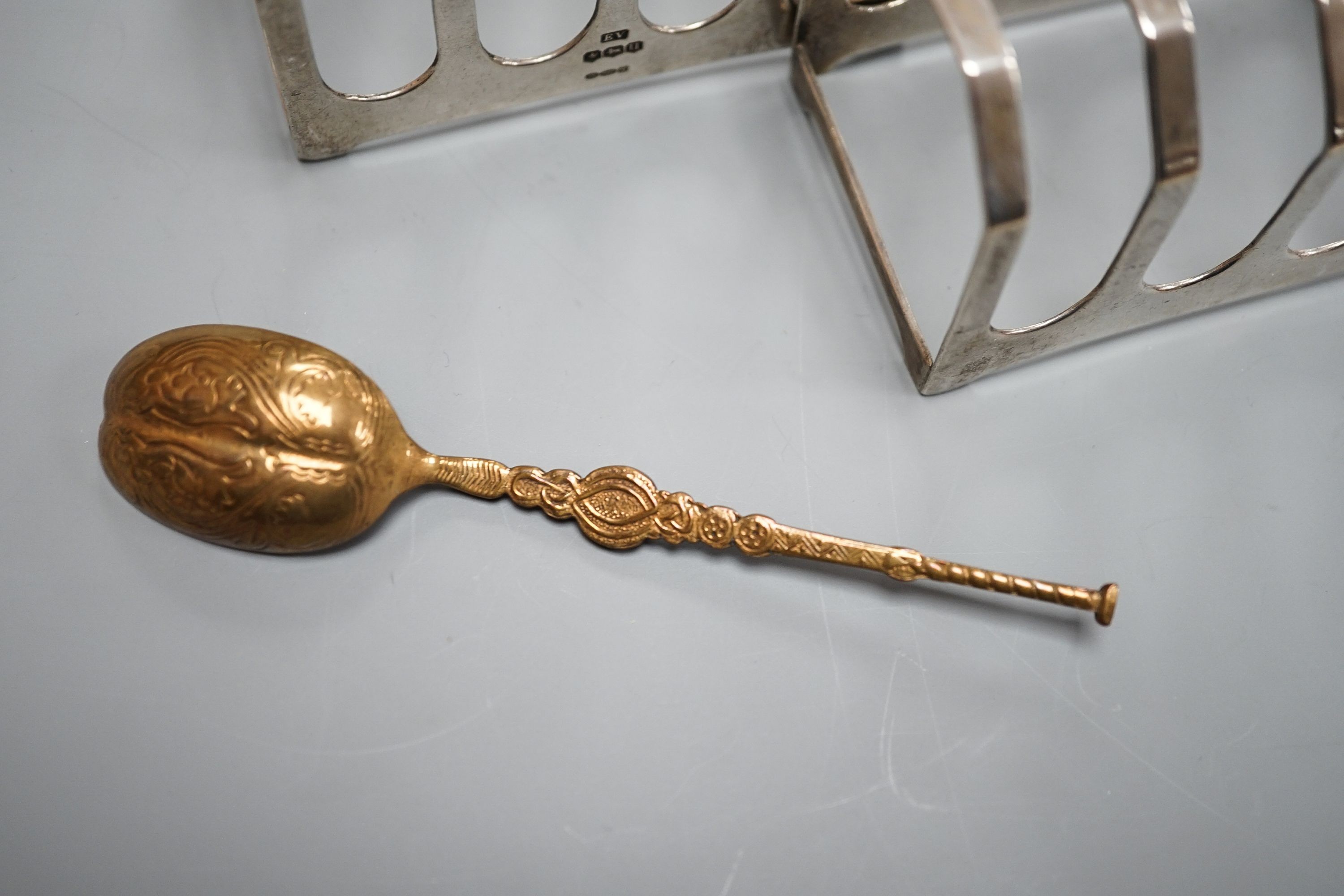 A pair of George VI silver five bar toastracks, Viner's Ltd, Sheffield, 1937, length 76mm and metal replica of a 12th century Coronation spoon.